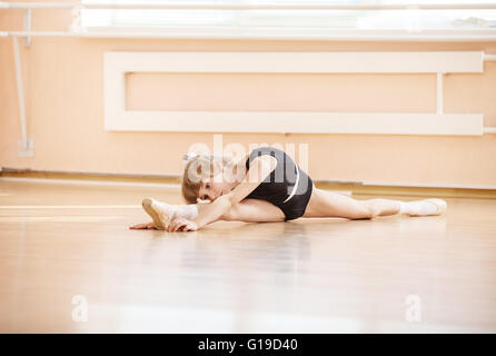 Junge Mädchen tun spaltet sich beim Aufwärmen am Ballett-Tanz-Workshop Stockfoto