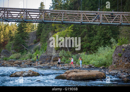 Radfahrer überqueren eine Brücke, während Fußgänger die Ufer des Flusses Spokane in Riverside State Park, Washington erkunden. Stockfoto