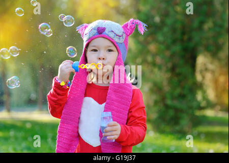 Mädchen mit Seifenblasen in einer Strickmütze Handarbeit Stockfoto