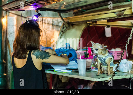 Eine Frau und ihren kleinen Hund stehen auf der Rückseite ein van als eine Bar auf den Straßen von Bangkok. Stockfoto