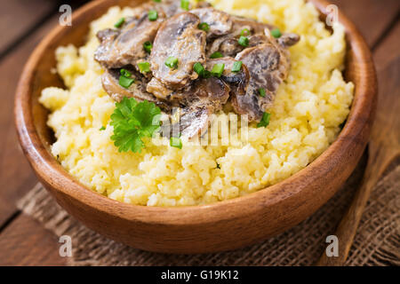 Hirsebrei mit Pilzen in einer Holzschale Stockfoto
