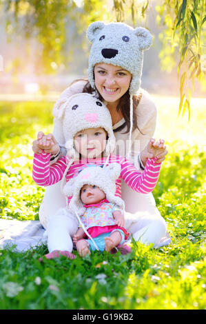 Mutter und Tochter in Strickmützen Bären, mit einer Puppe Stockfoto