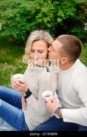 Junge schöne Paar umarmt unter einer Decke im Park. Te Stockfoto