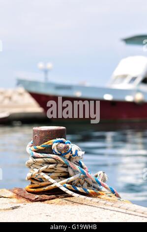 Marine Seil am Liegeplatz Poller im Hafen von Podgora, Kroatien.  Verschwommene Schiff auf Hintergrund Stockfoto