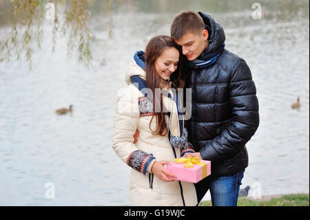 Der junge Mann gibt ein Geschenk, einem jungen Mädchen in das Café und Sie Stockfoto