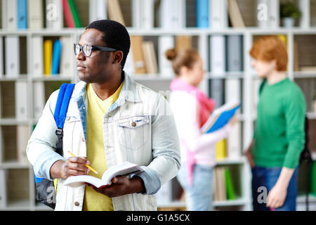 Nachdenkliche Schüler im Casual-Wear und Brillen immer bereit für Seminar in College-Bibliothek Stockfoto
