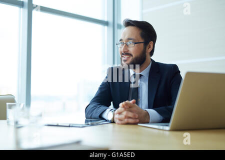 Glücklich asiatischen Geschäftsmann am Arbeitsplatz im Büro sitzen Stockfoto