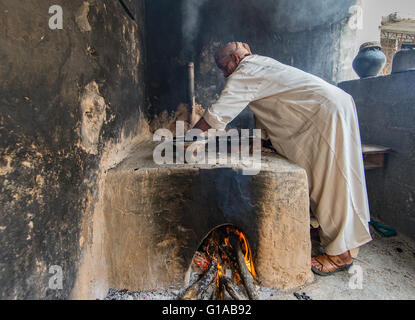 Jabal Al Akhdar, Oman - April 2016: Ein Greis omanischen ist Rosenwasser aus Rosenblättern mit traditionellem Ofen extrahieren Stockfoto