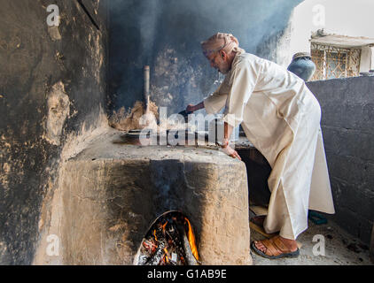 Jabal Al Akhdar, Oman - April 2016: Ein Greis omanischen ist Rosenwasser aus Rosenblättern mit traditionellem Ofen extrahieren Stockfoto