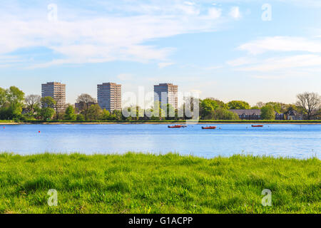 Frühlings-Blick auf Stoke Newington West Reservoir, Hackney, London mit grünen Rasen, blauer Himmel und ein paar schwimmende Boote Stockfoto