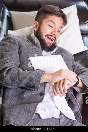 Verschlafene Geschäftsmann mit einem Tablet-Gerät auf einem sofa Stockfoto