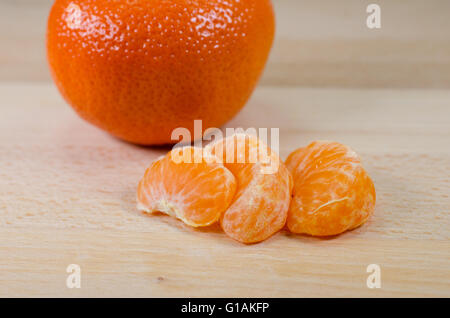 Mandarine Segmente und ganze Mandarine auf einem Holztisch Stockfoto