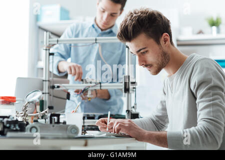 -Studenten arbeiten im Labor, ist ein Student einen 3D-Drucker im Hintergrund verwenden. Stockfoto