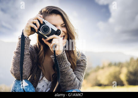 Junge weibliche Fotografen sitzen auf dem Rasen und fotografieren, Naturlandschaft auf Hintergrund Stockfoto