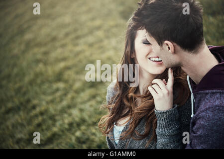 Junges Liebespaar auf dem Rasen sitzen, ist sie flirtet mit ihm, Liebe und Beziehungen-Konzept Stockfoto
