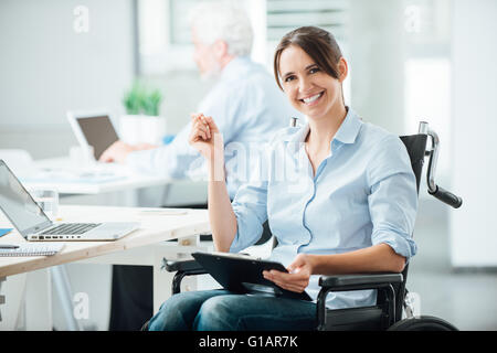 Glücklich weibliche Büroangestellte im Rollstuhl hält ein Klemmbrett und lächelt in die Kamera, Unterstützung von Menschen mit Behinderungen am Arbeitsplatz Stockfoto