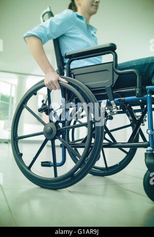 Junge Frau im Rollstuhl Hand drücken am Rad in der Nähe von Behinderung und Handicap-Konzept Stockfoto
