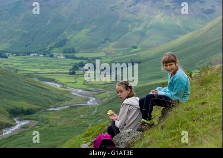 Zwei Kinder beim Mittagessen auf dem Weg von Wasdale Head, landschaftlich Tarn mit Lingmell Beck hinter. Cumbria UK Stockfoto