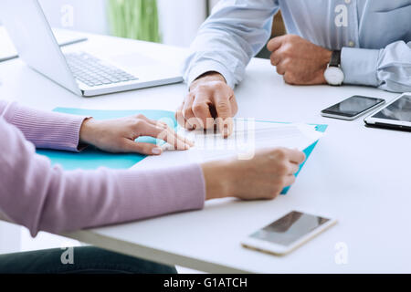 Junge Frau mit einem Geschäft treffen mit Führungskraft in seinem Büro, er zeigt auf einen Vertrag und Erklärungen Stockfoto