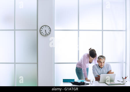 Executive mit seiner Assistentin am Schreibtisch arbeiten, sie sind benutze ein Laptop und Internetverbindung Stockfoto