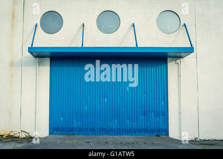 Blaues Tor an einer Grunge Wand mit runden Fenstern Stockfoto