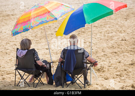 Bournemouth, Dorset, Großbritannien 12. Mai 2016. Paar erholsame auf Bournemouth beach unter bunten Sonnenschirmen Credit: Carolyn Jenkins/Alamy Live News Stockfoto