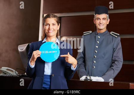 Frau auf deutschen Schild mit der Aufschrift "Willkommen" (willkommen) an der Rezeption Stockfoto