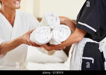 Magd bringen frische Handtücher während der Zimmerreinigung im Hotelzimmer Stockfoto