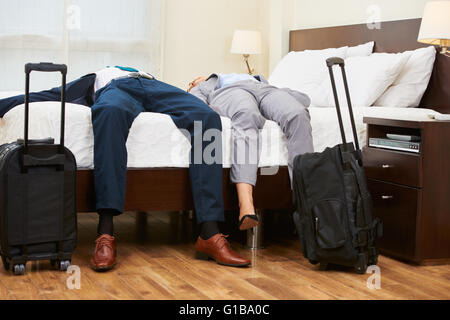 Zwei müde Geschäftsleute auf Bett in einem Hotelzimmer Stockfoto