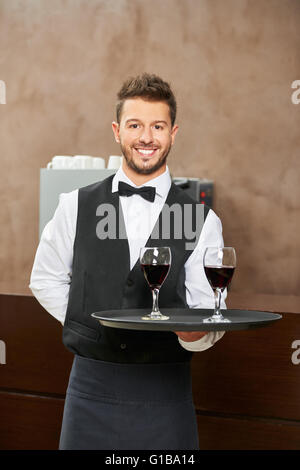 Kellner in Uniform Rotwein im Restaurant des Hotels serviert Stockfoto