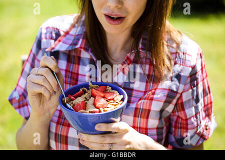 Porträt einer Frau außerhalb essen gesundes Müsli mit frischen Erdbeeren Früchte Stockfoto