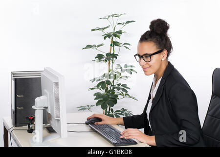 Jung, sitzt am Schreibtisch im Büro und arbeiten am pc schöne Geschäftsfrau Stockfoto