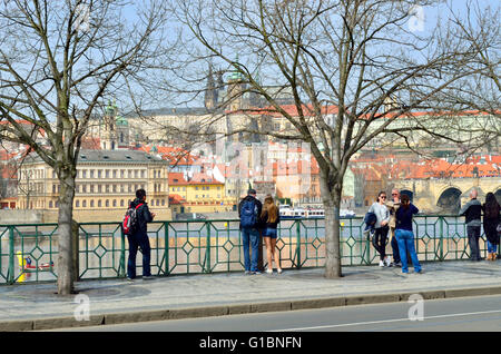 Prag, Tschechische Republik. Smetana Nabrezi / Smetana Embankment. Blick auf die Burg über dem Fluss, Menschen auf dem Damm Stockfoto