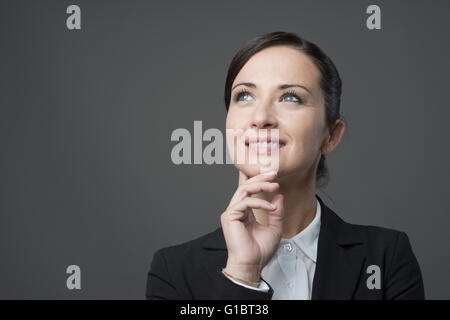 Lächeln charmante Geschäftsfrau mit Hand am Kinn wegsehen. Stockfoto