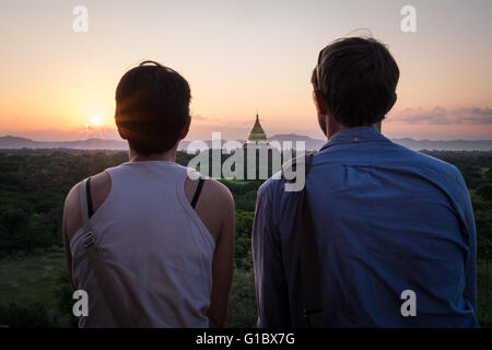 Eine Paaruhr aus der Spitze von einem Tempel in Bagan als die Sonne untergeht. Stockfoto