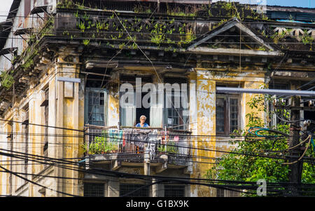 Eine Frau hängen Wäsche auf ihrem Balkon in der Innenstadt von Yangon Stockfoto