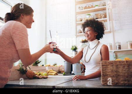 Weiblichen Barkeeper dient ein Glas frischen Orangensaft, Frau in eine Saftbar. Saft-Bar-Mitarbeiter, die trinken an Kunden. Stockfoto