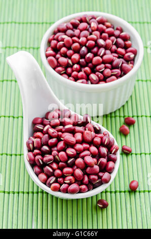 Azuki Bohnen, rote Bohnen in weißer Löffel auf grüne Bambusmatte. Stockfoto