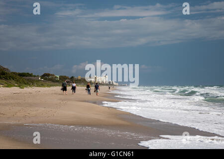 Indialantic, Florida - Menschen gehen in Richtung high-Rise Kondominien und Hotels am Strand. Stockfoto