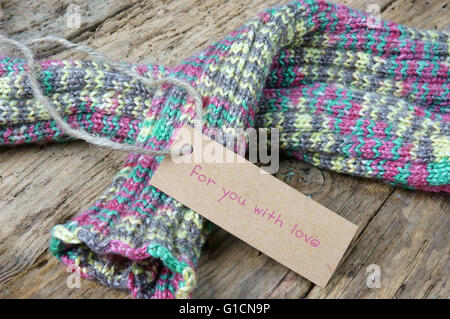 Frauen Hand stricken Wolle Handschuh zu Weihnachtsgeschenk, ein besonderes Geschenk für kalte Winter, bunte Wolle Ball, hölzernen Hintergrund Stockfoto