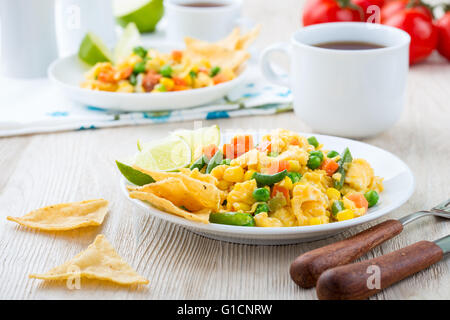 Hausgemachte mexikanischer Salat Rührei Ei serviert mit gebackenen Mais-Tortilla-Chips und Keil von Kalk, gesundes Frühstück Stockfoto