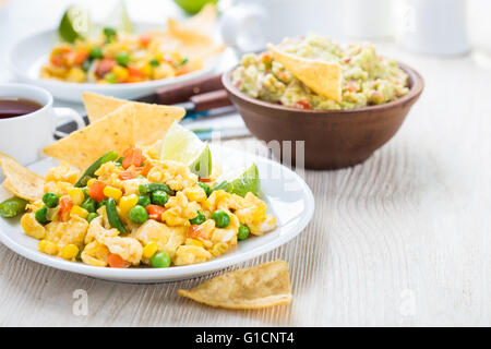 Hausgemachte mexikanischer Salat Rührei serviert mit Mais-Tortilla-Chips und Guacamole, gesundes Frühstück Stockfoto