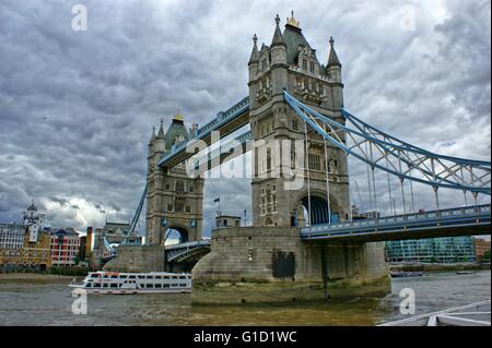 London Bridge, nahe dem Tower of London, dramatischen Blick mit bewölktem Himmel und alten Steinmauern Stockfoto