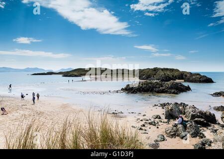 Ein Blick auf Ynys Llanddwyn vom Festland Anglesey (Ynys Mon). Menschen sind Fuß auf die zurückweichenden Flut, die Insel zu erreichen. Stockfoto