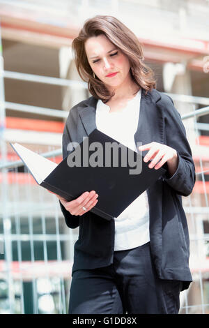 junge Frau stand vor der Baustelle und Blick auf Buch Stockfoto