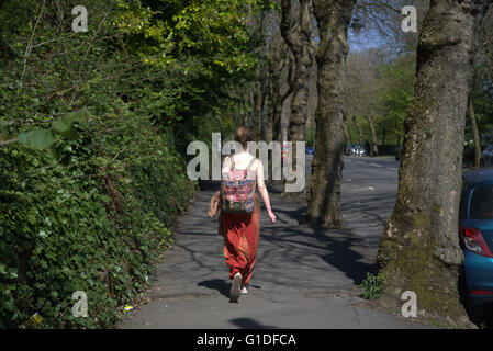 Zweitens attraktiv gekleidet junge Frau in hellen Farben mit Rucksack Kelvingrove Park, Glasgow, Schottland, UK. Stockfoto