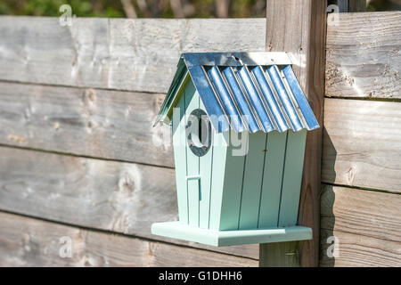 Niedliche Vogelhäuschen hängen an einem Holzzaun in einem Garten Stockfoto