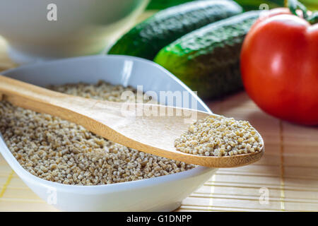 Ungekocht Buchweizen-Nudeln für Tarhana Suppe mit Tomaten, Gurken und weiße Schale im Hintergrund Stockfoto