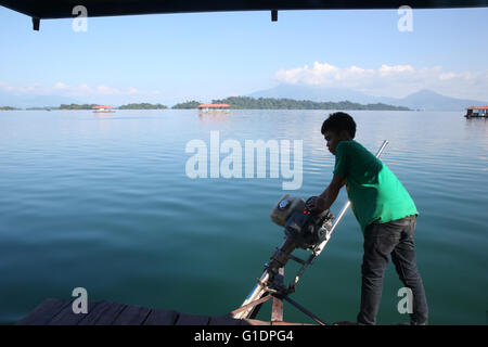 Nam Ngum See.  Junge Lenkung eine traditionelle Lao-Motorboot. Laos. Stockfoto