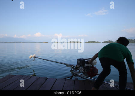 Nam Ngum See.  Junge Lenkung eine traditionelle Lao-Motorboot. Laos. Stockfoto